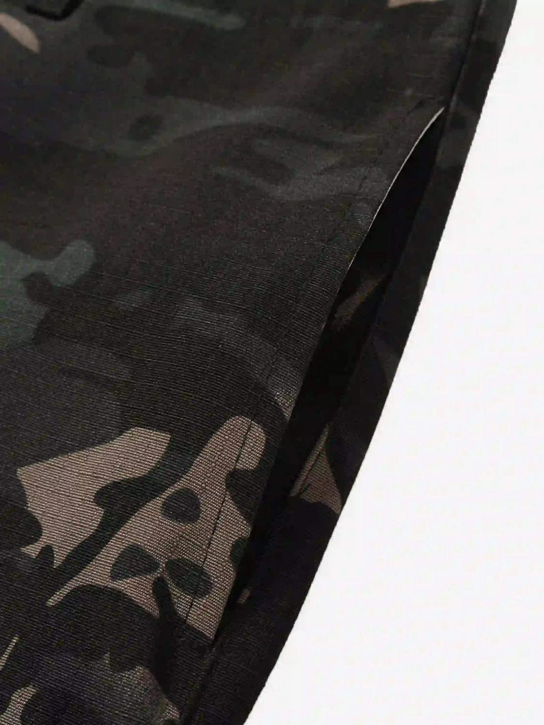 Detailed fabric and stitching on TALISHKO's dark camouflage cargo pants, highlighting style.