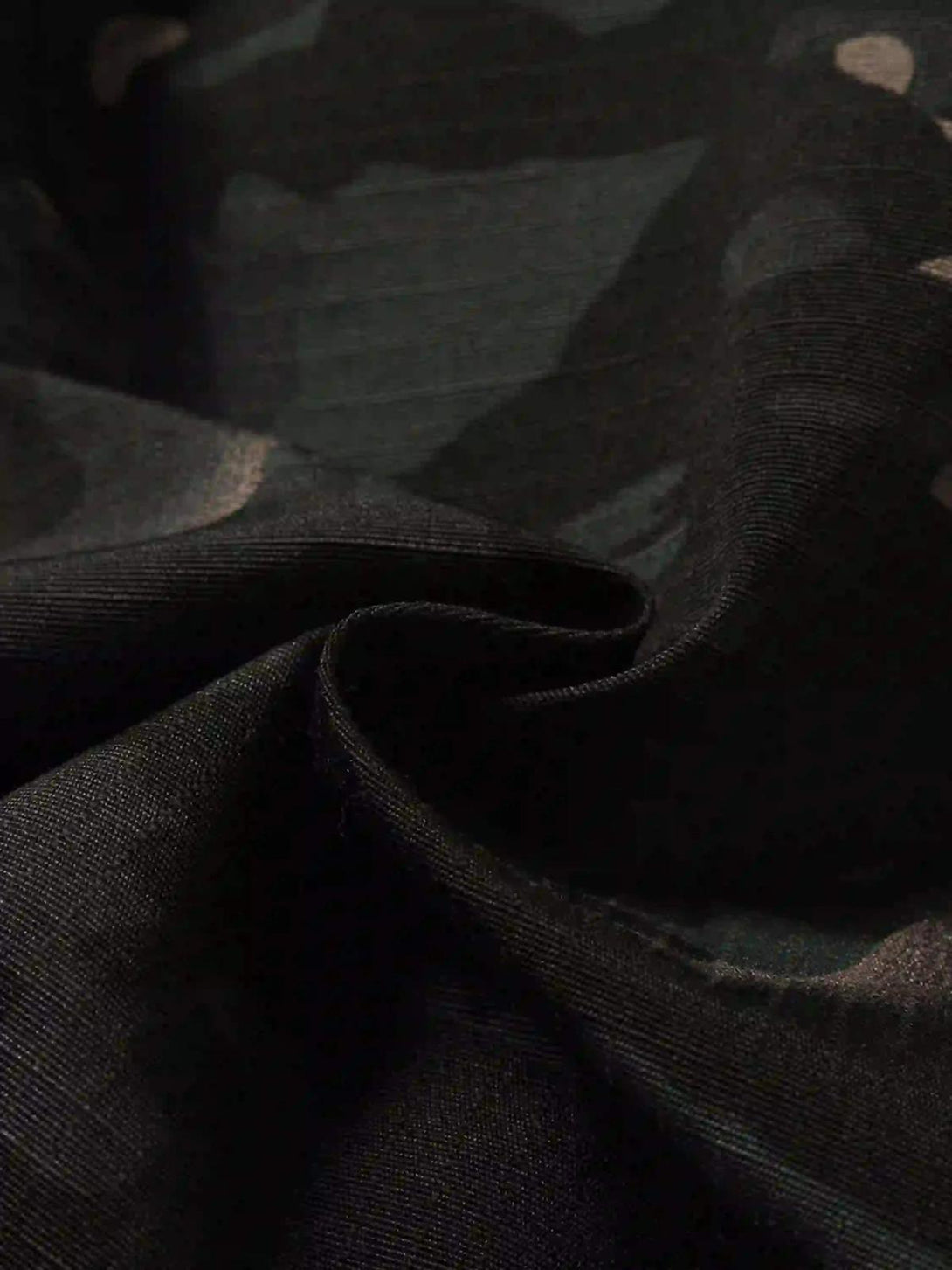 "Zoomed-in texture of TALISHKO cargo pants showing dark camouflage pattern and fabric detail."