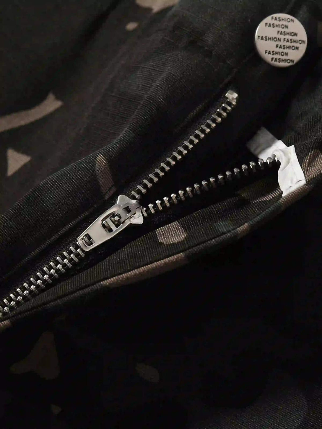 Intricate look at TALISHKO camouflage cargo pants zipper, showcasing detailed fabric design.