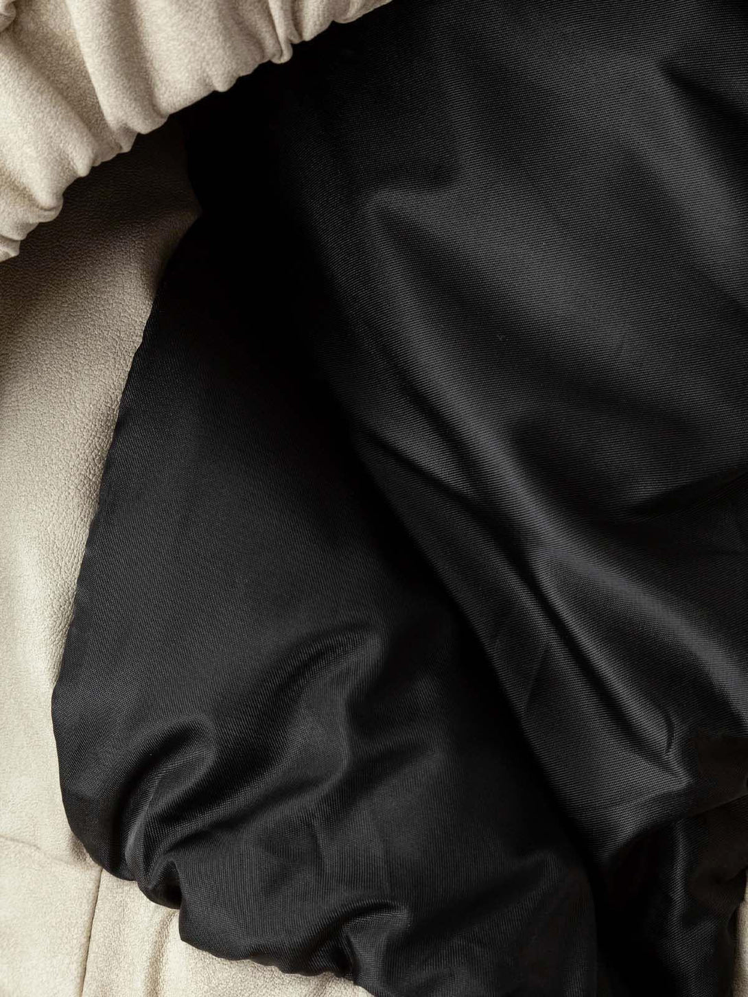 Detailed fabric and stitching of TALISHKO's suede padded puffer jacket in beige and black.
