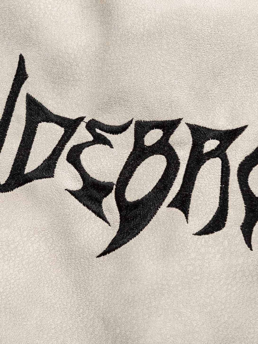 A close-up of TALISHKO's suede puffer jacket, highlighting bold flame embroidery detail.