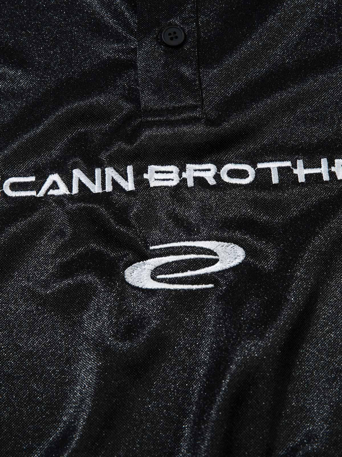 A close-up of the black TALISHKO polo, highlighting embroidered logo details and texture.