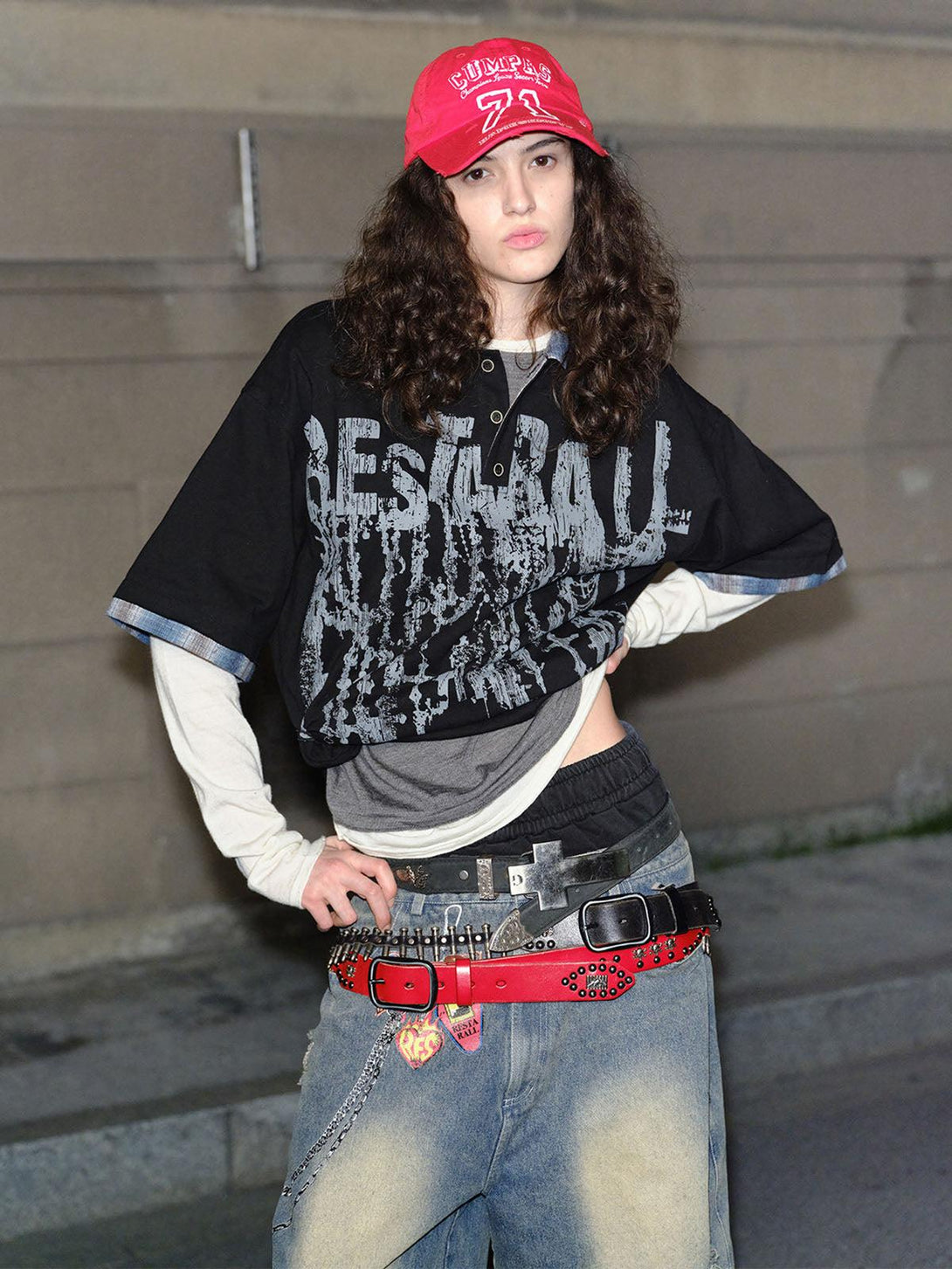 Model wearing TALISHKO graffiti polo shirt layered over casual streetwear, featuring a red cap.