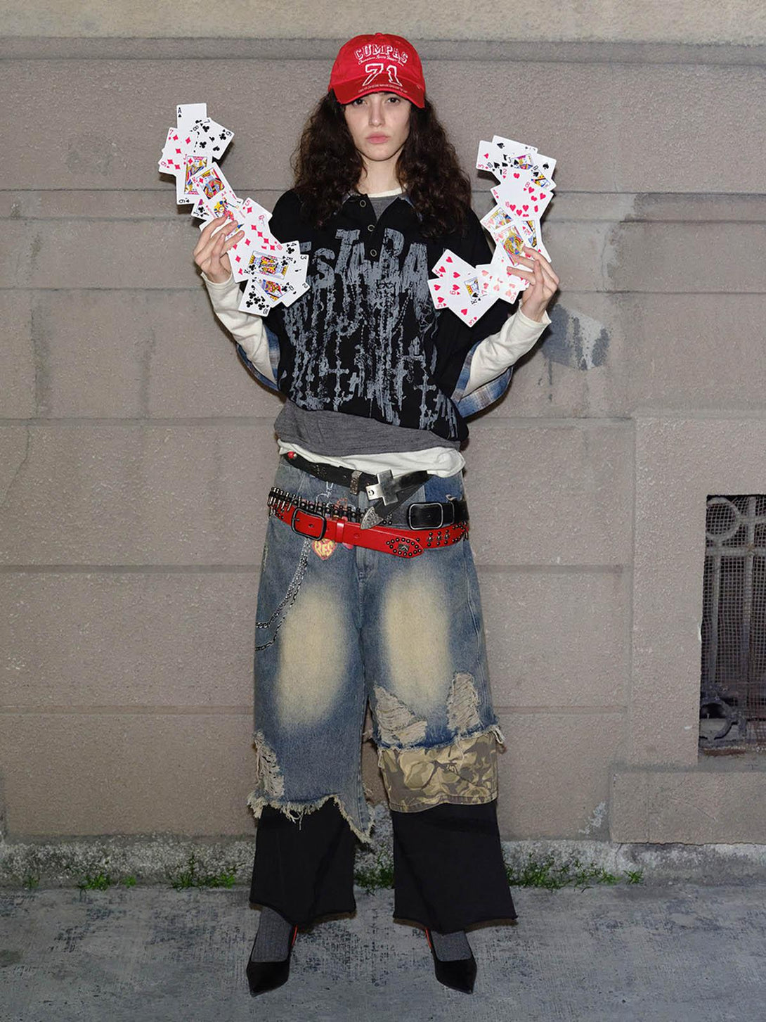 Model showcasing TALISHKO graffiti polo shirt with layered streetwear and playing cards.