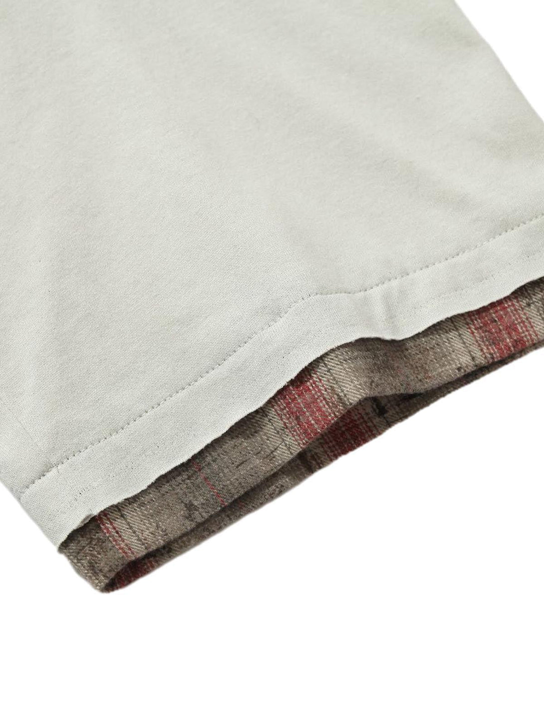 "A detailed view of TALISHKO polo shirt's hem with plaid lining, showcasing layered texture."