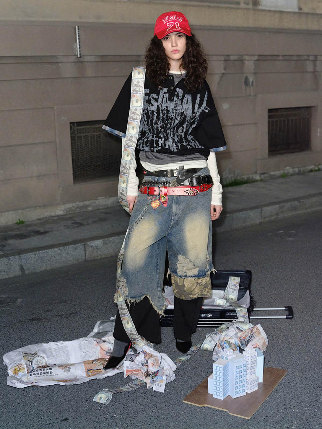 Model in TALISHKO street-style polo with graffiti print and layered urban outfit, on city street.