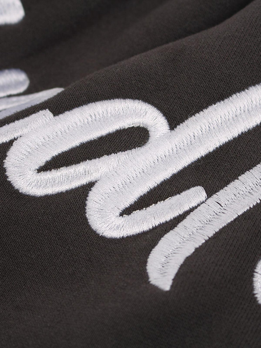 Zoomed-in texture of TALISHKO drawstring shorts highlighting white embroidered text detail.