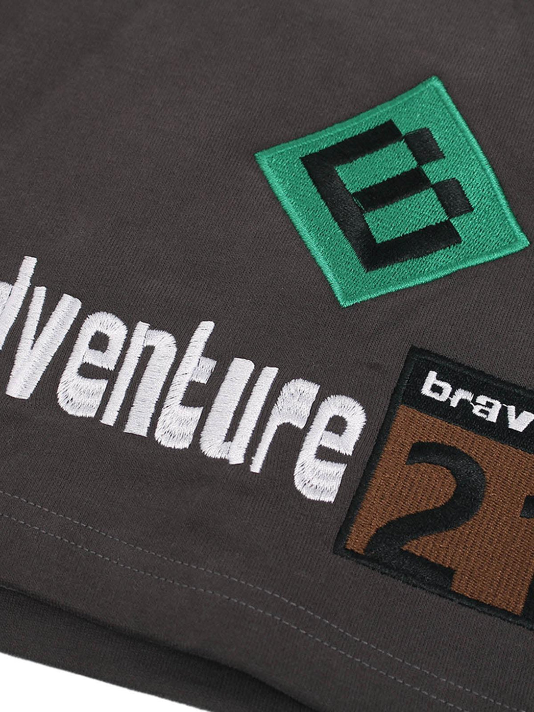 A detailed view of TALISHKO drawstring shorts, highlighting graphic patches and embroidery.