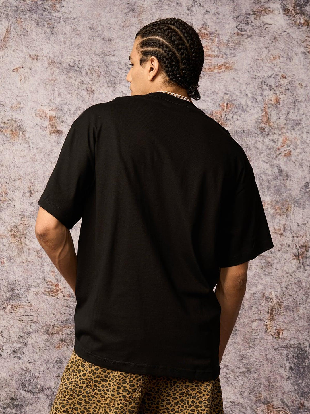 Model wearing a black TALISHKO T-shirt with leopard print shorts, showcasing urban style.