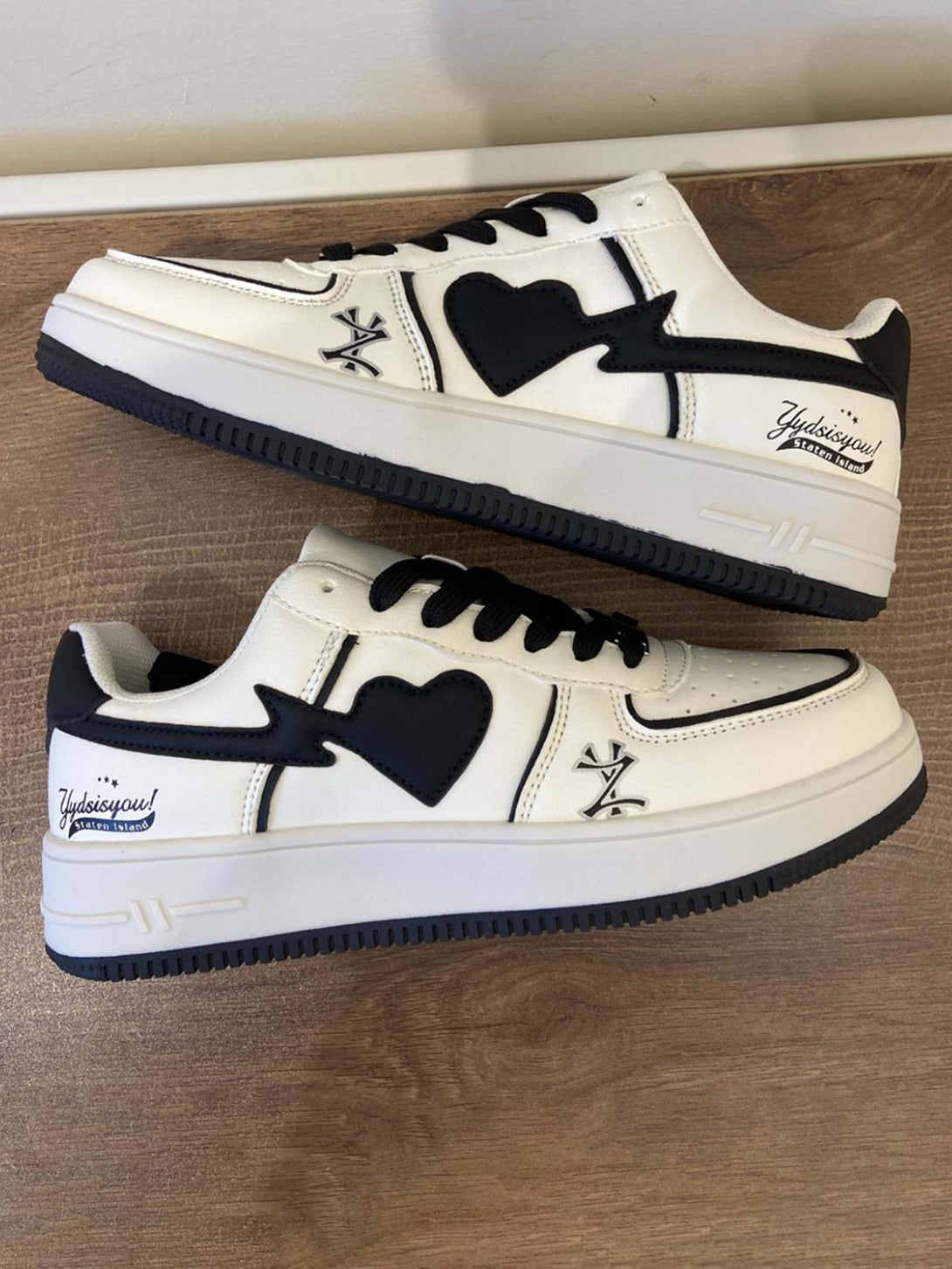 TALISHKO skate shoes with black heart accents and bold street style on a wooden surface.