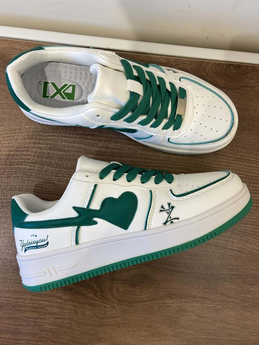 White and green skate shoes by TALISHKO, featuring a heart design and vibrant laces.