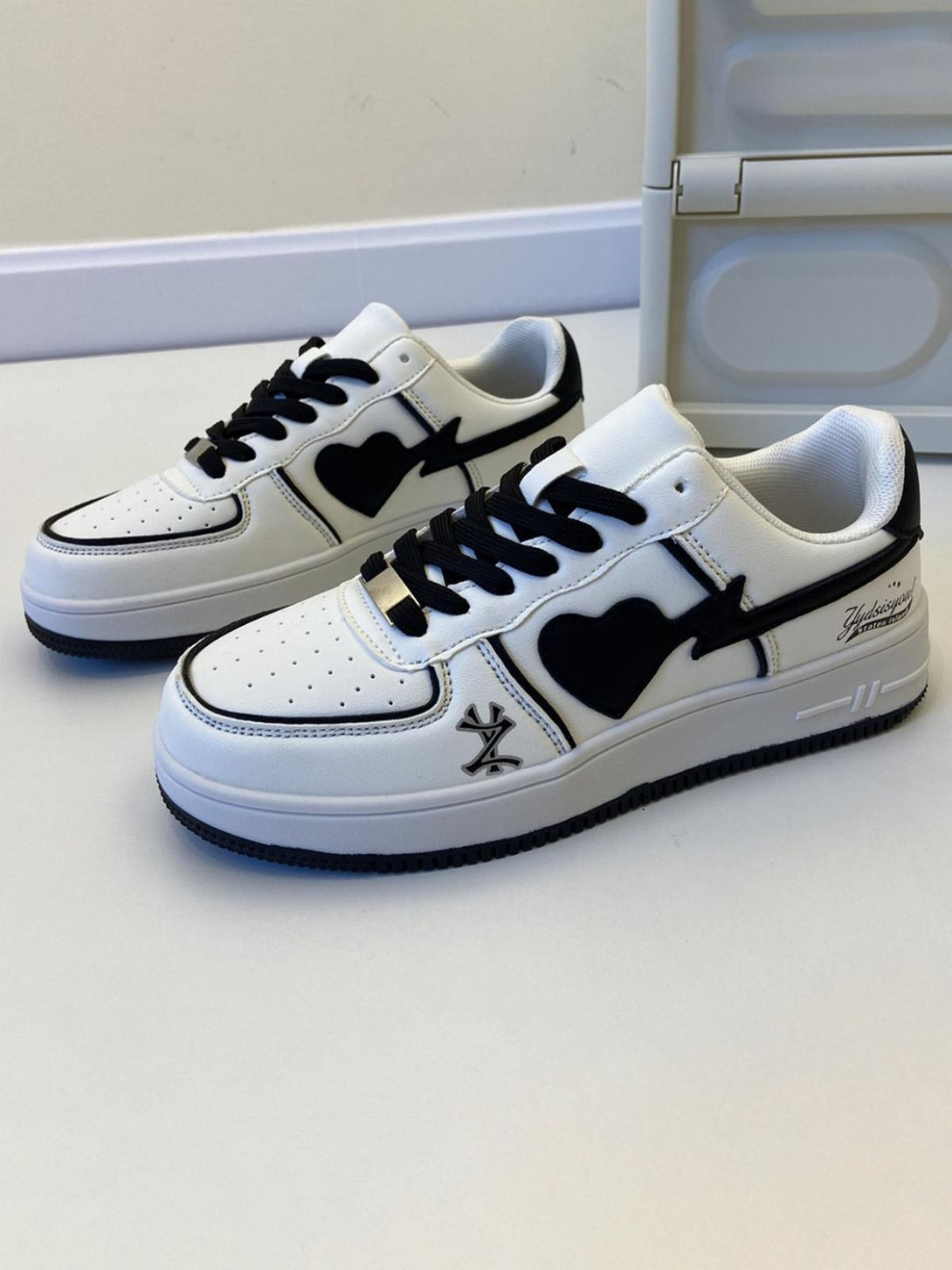 White skate shoes by TALISHKO featuring black heart design and bold streetwear style.