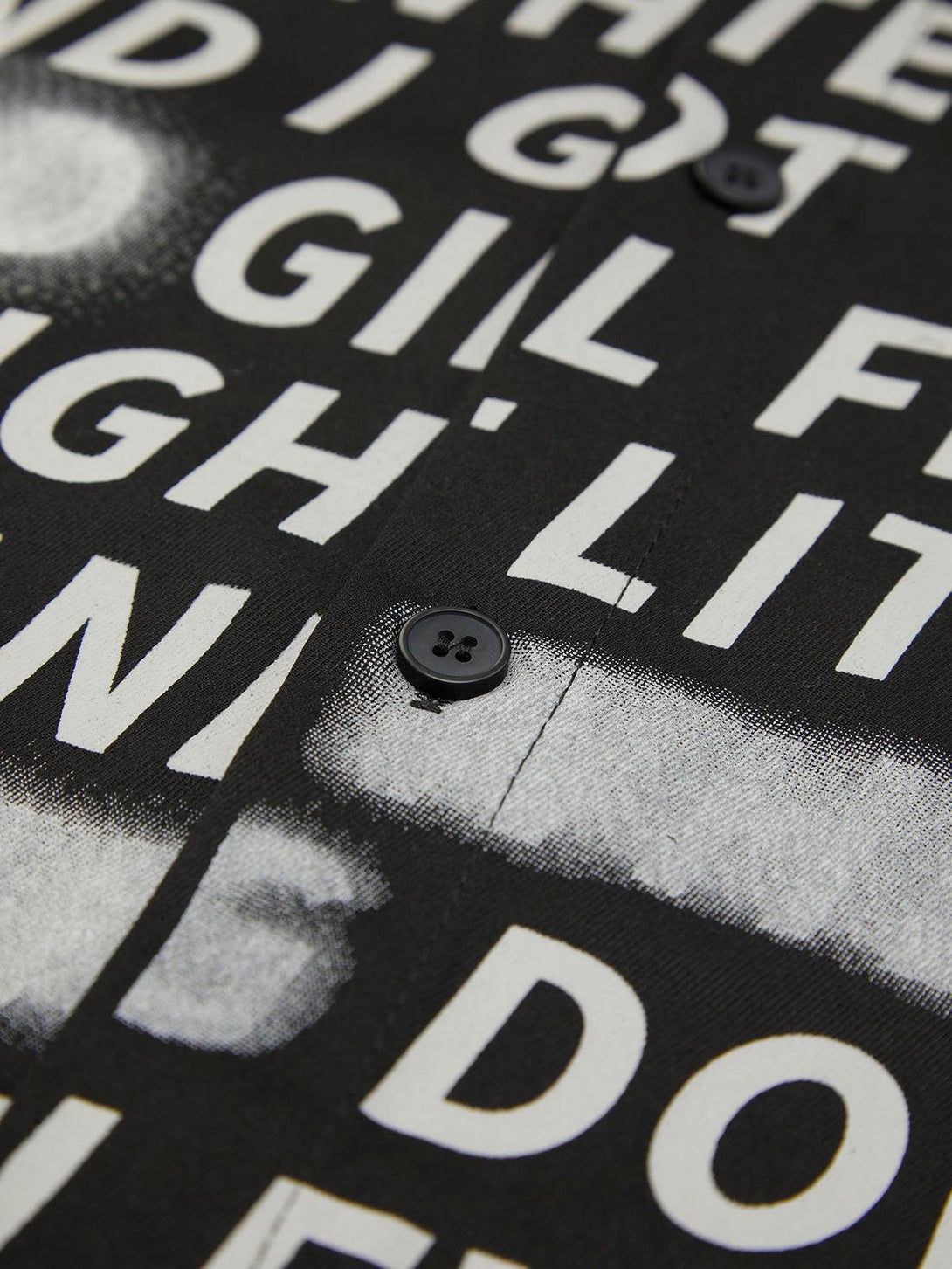 Intricate look at TALISHKO's shirt highlighting bold letter print and button detail.
