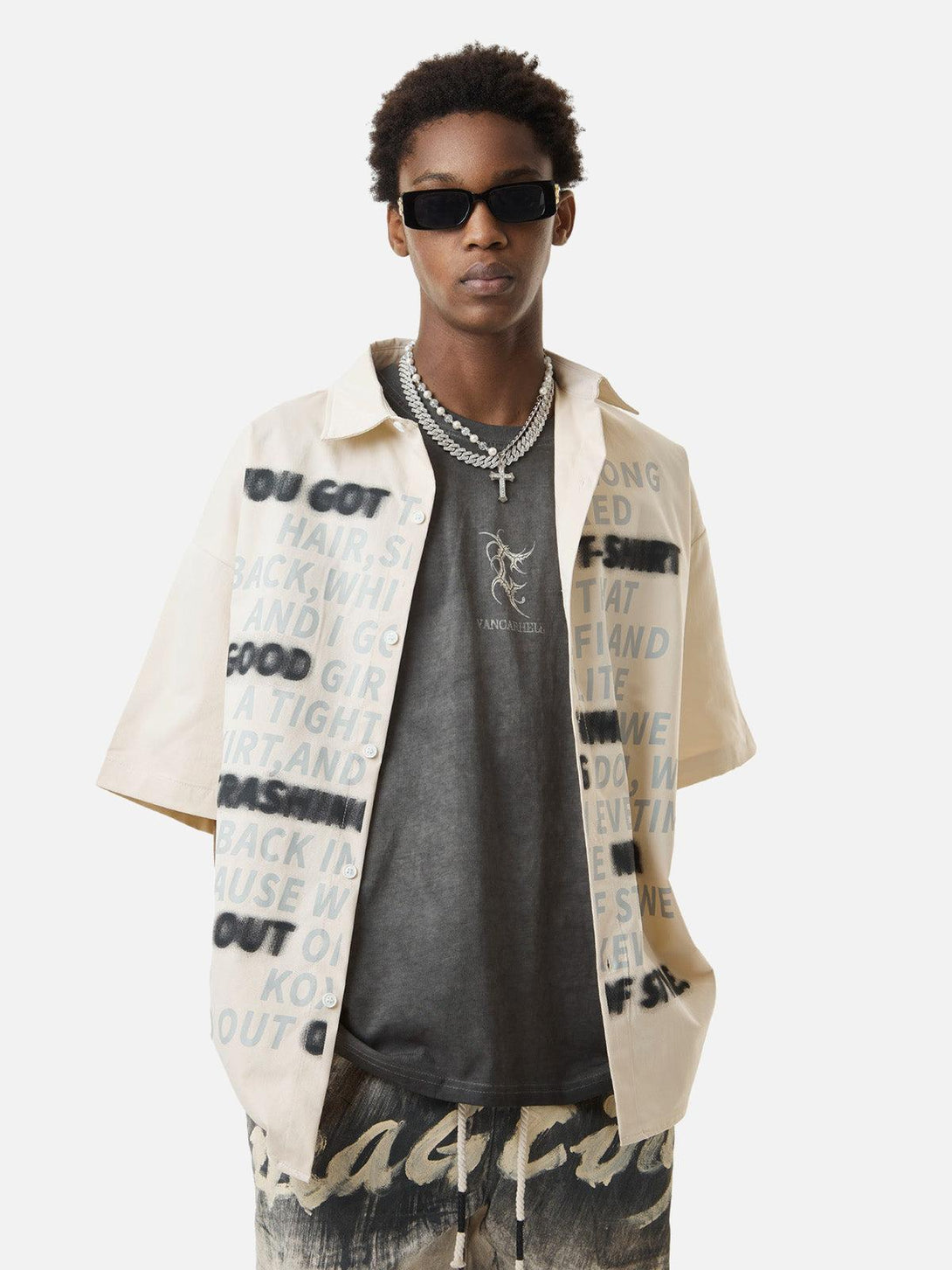 Model wearing TALISHKO street-style letter print shirt with layered chains and sunglasses.