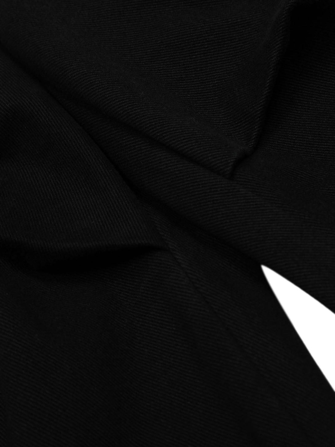 Detailed view of TALISHKO cargo jorts, showcasing the black fabric texture and pleated detail.