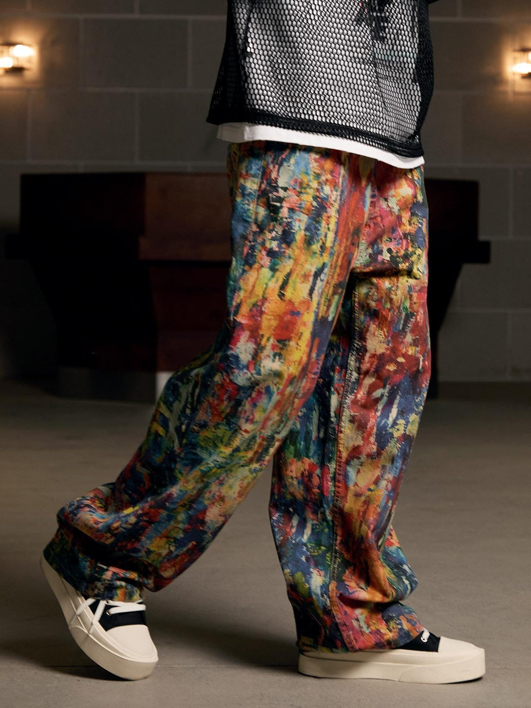 TALISHKO's vibrant oil painting patterned jeans are styled with casual sneakers for a bold look.