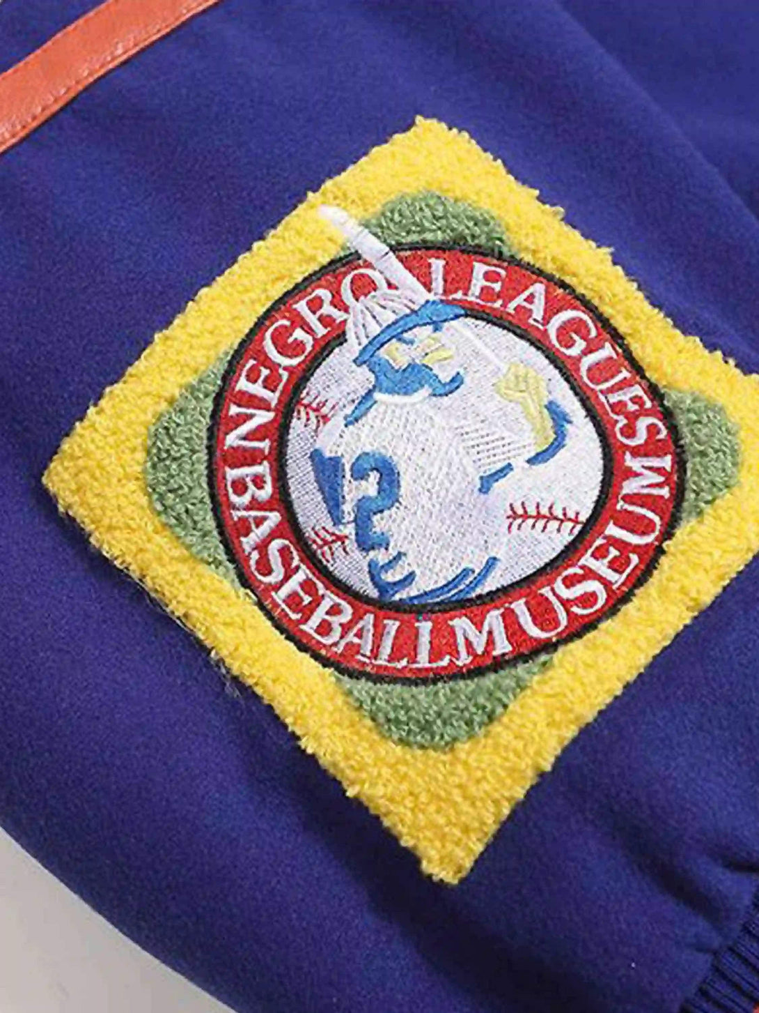 Zoomed-in detail of a TALISHKO baseball jacket showcasing vibrant embroidered patchwork.