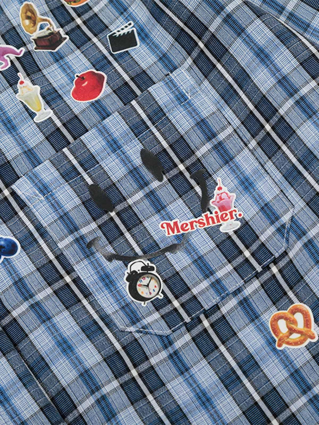 Focusing on the playful sticker details on TALISHKO's blue plaid shirt, adding a retro vibe.