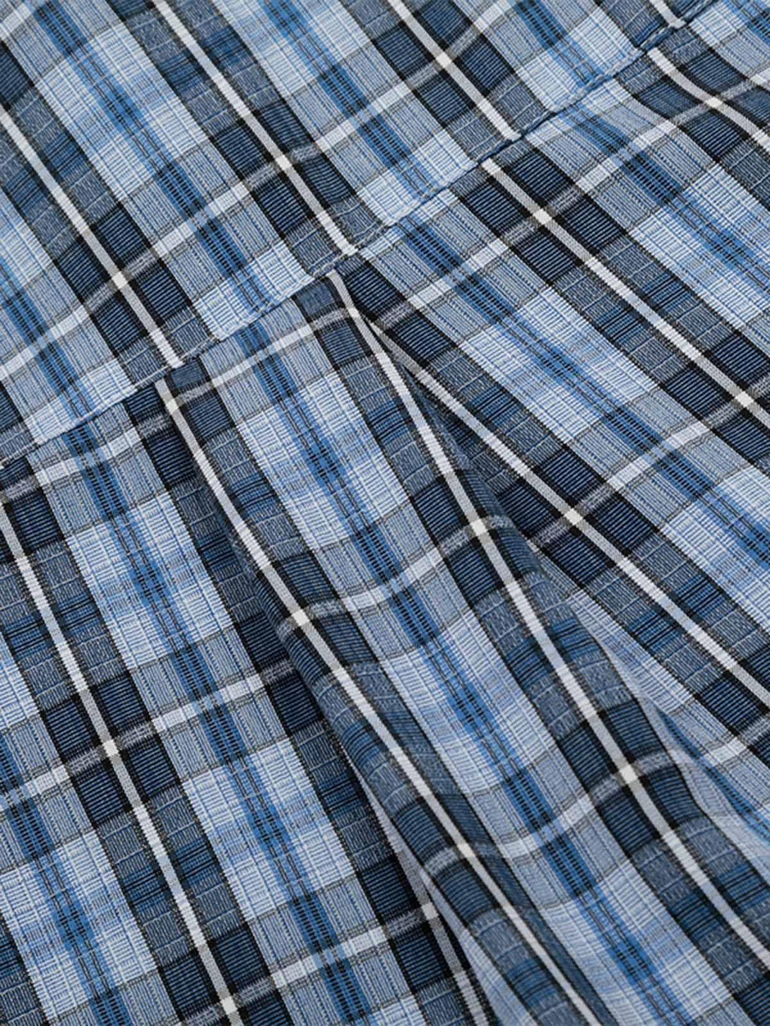 Zoomed-in texture of TALISHKO's plaid shirt, featuring a blue and black checkered pattern.
