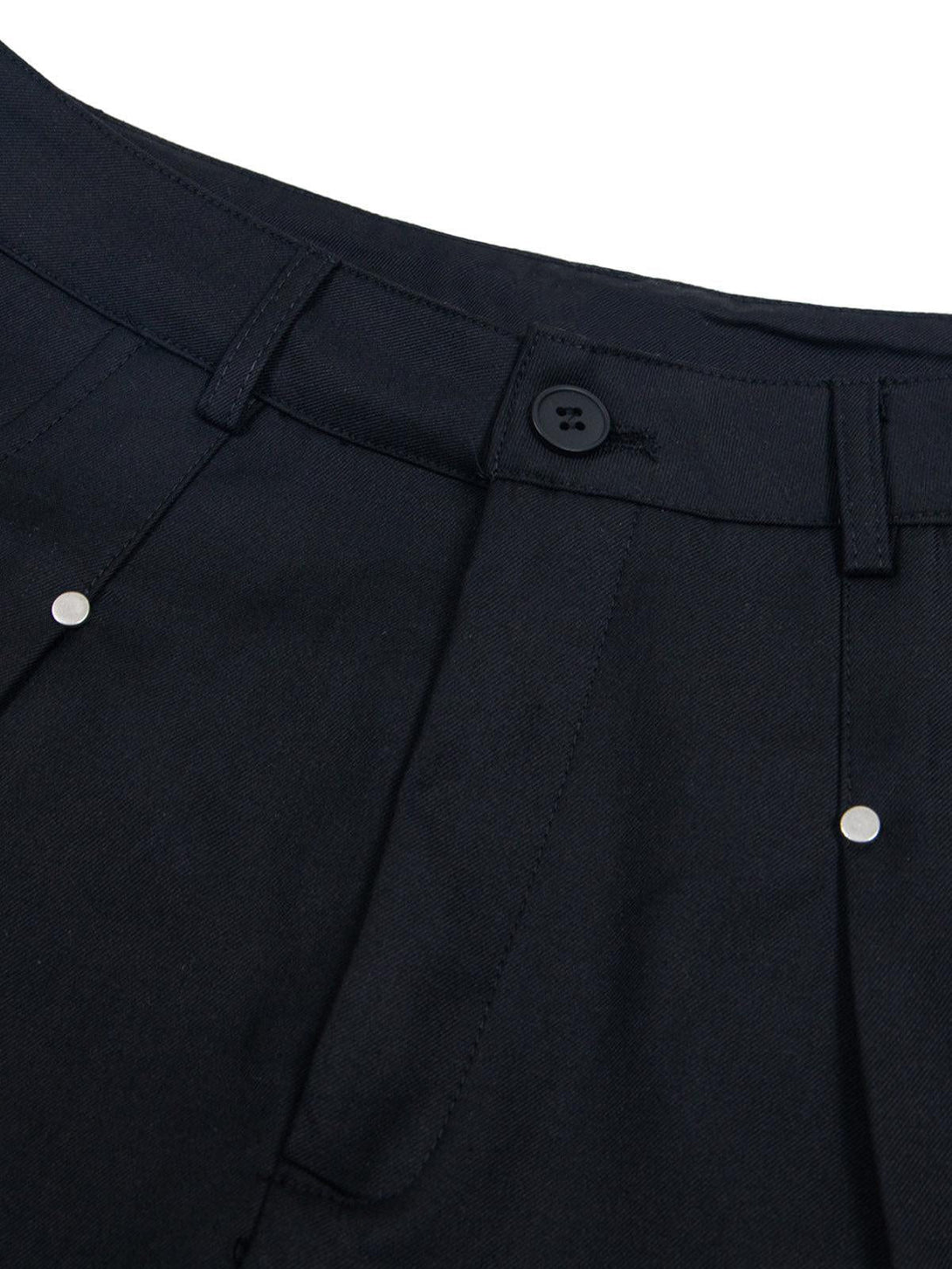 Detailed view of black pleated shorts by TALISHKO, highlighting rivet accents and retro design.
