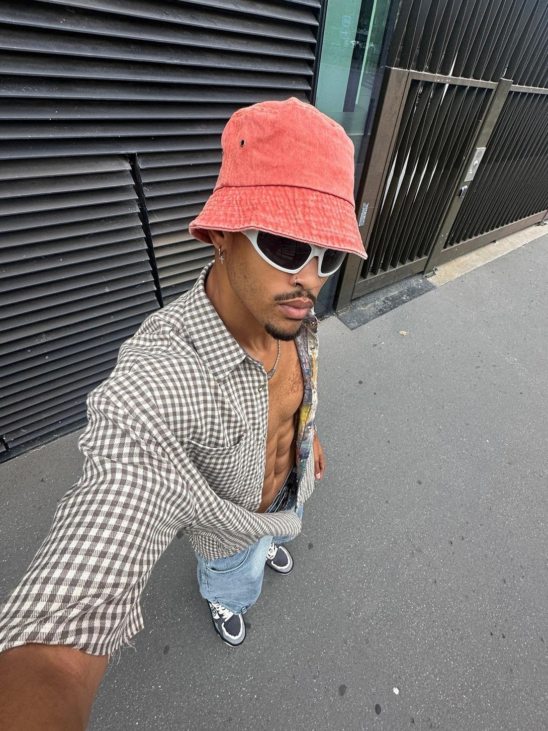Model in a TALISHKO reversible short-sleeved shirt, styled with a red bucket hat and jeans.