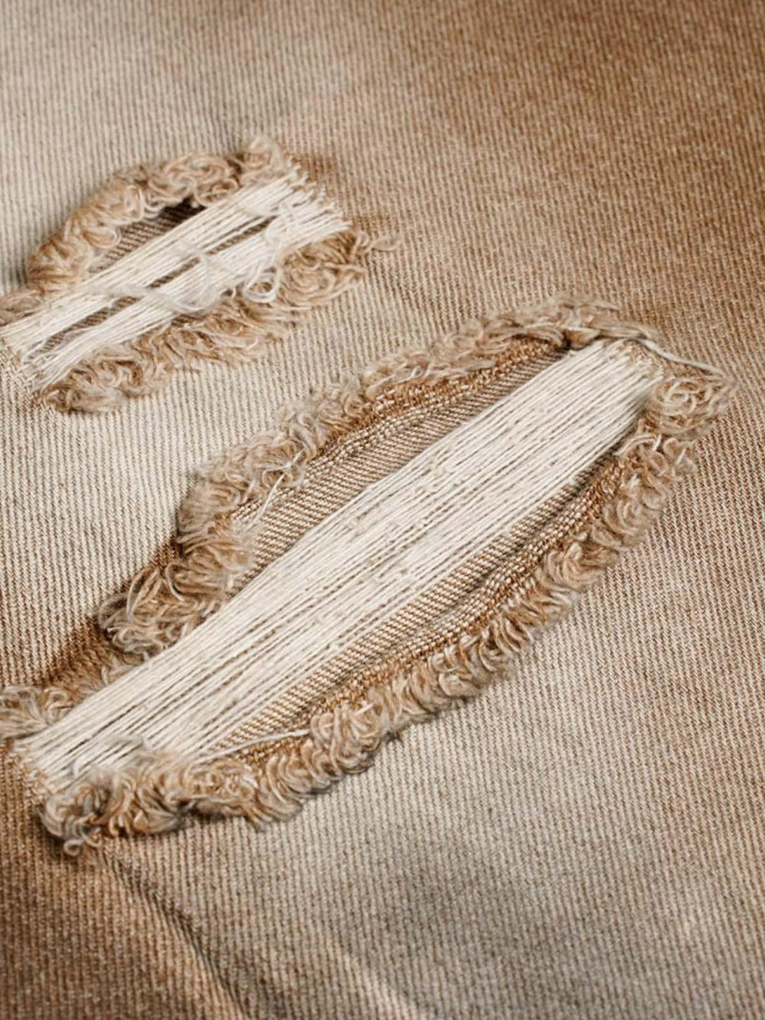 Intricate look at the distressed details on TALISHKO street jeans, showcasing edgy style.