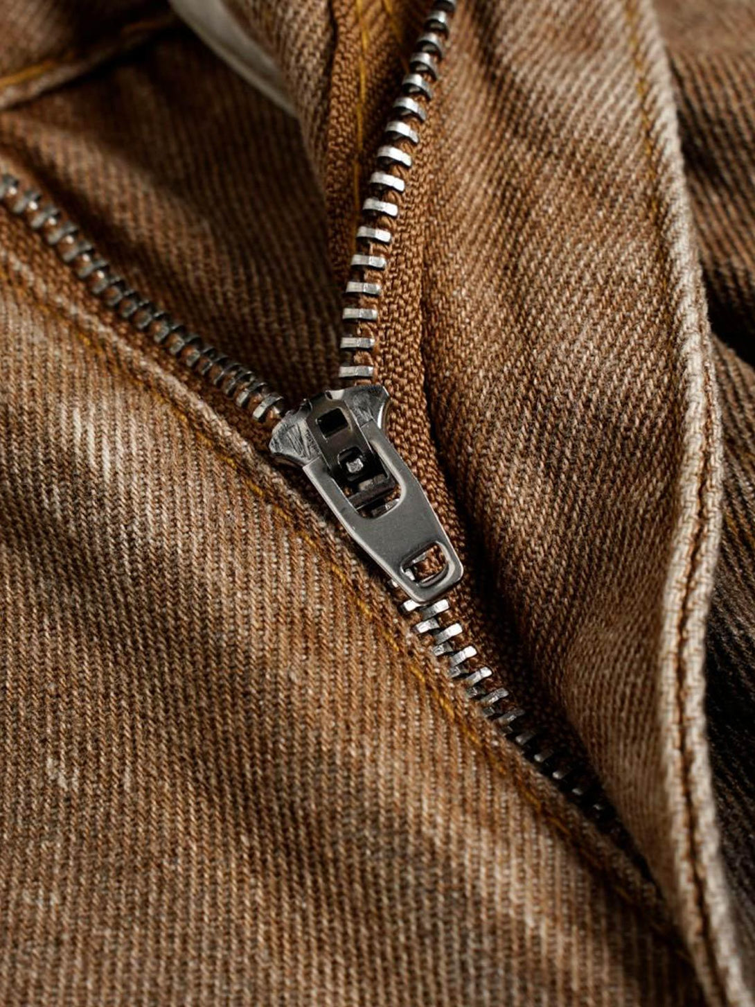 A close-up of the zipper detail on TALISHKO's street jeans, highlighting the rugged texture.