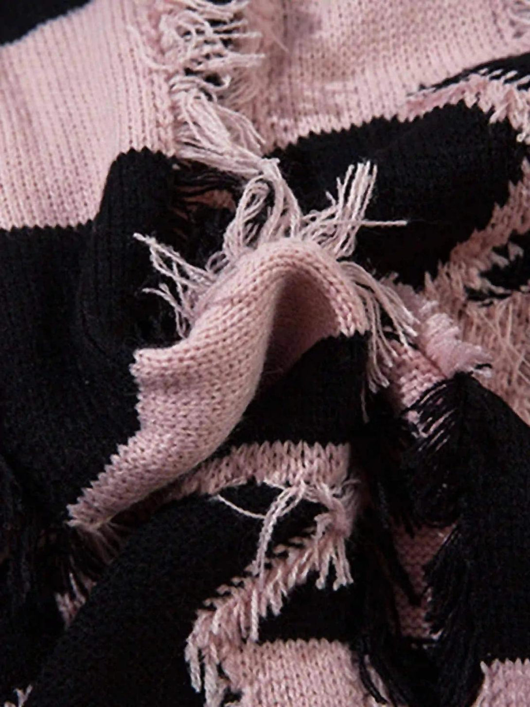 A close-up of TALISHKO sweater's pink and black stripes with frayed, distressed texture.