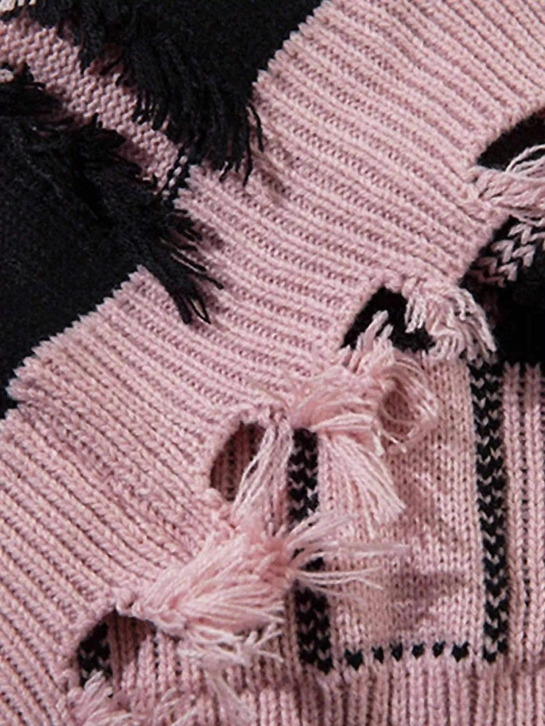 Detailed fabric and stitching of TALISHKO sweater, featuring pink and black distressed texture.