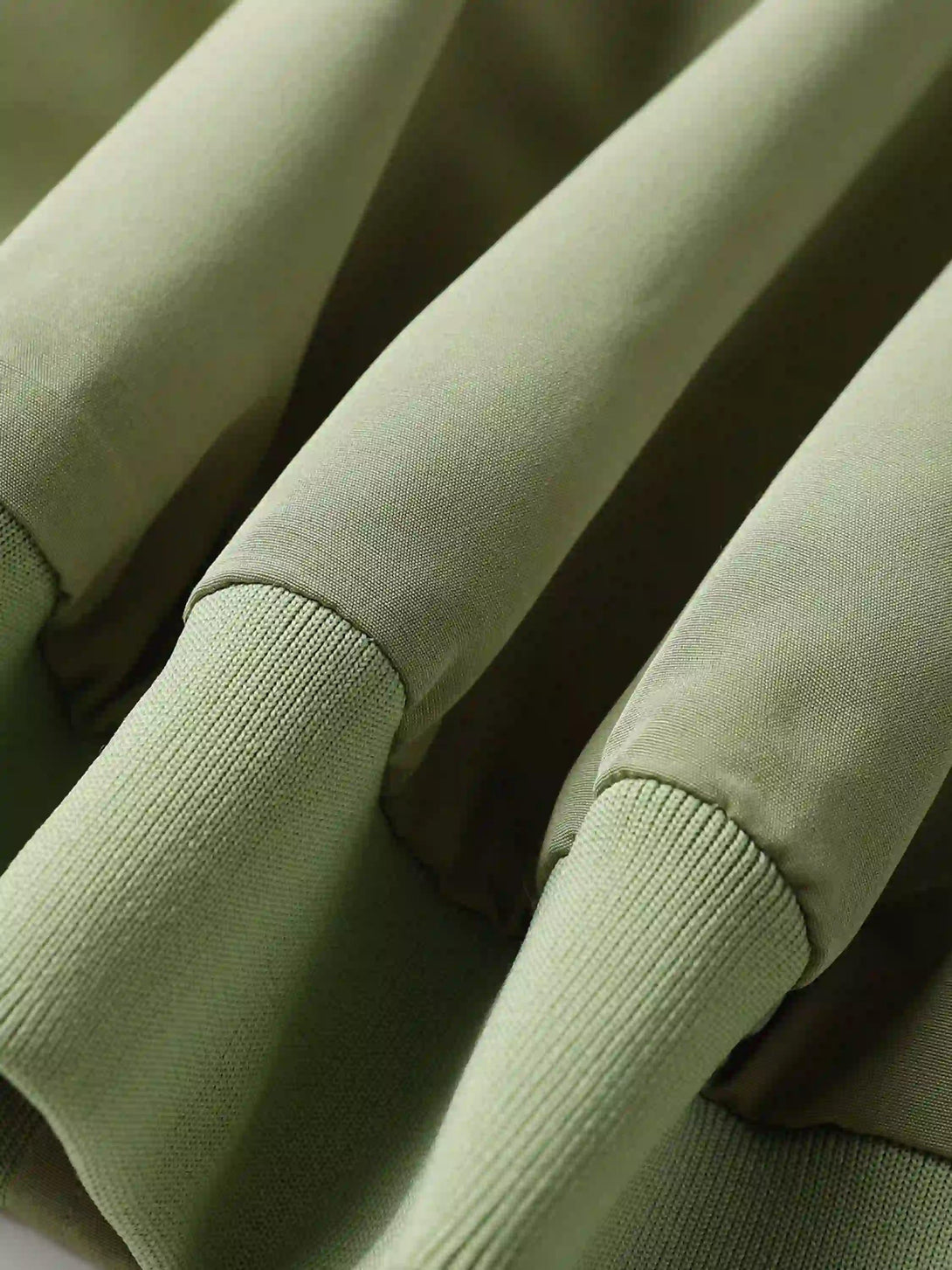 Detailed fabric and stitching on TALISHKO's green zip-up jacket, highlighting quality design.
