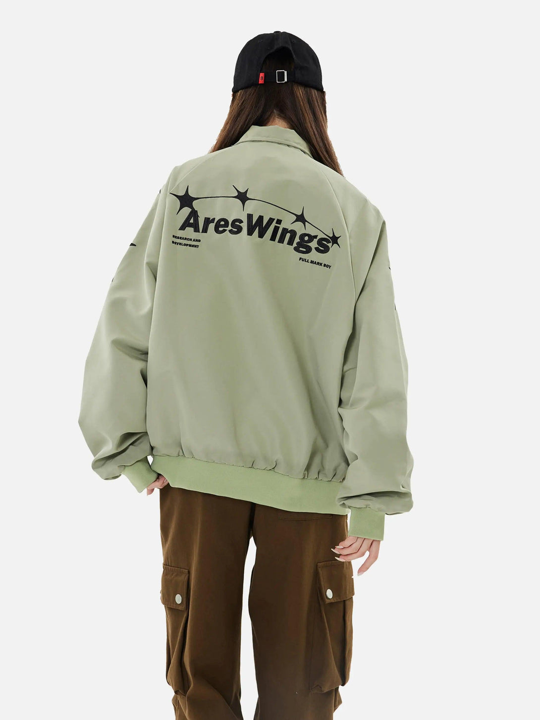 Model in green TALISHKO zip-up jacket with star design on back, paired with cargo pants.