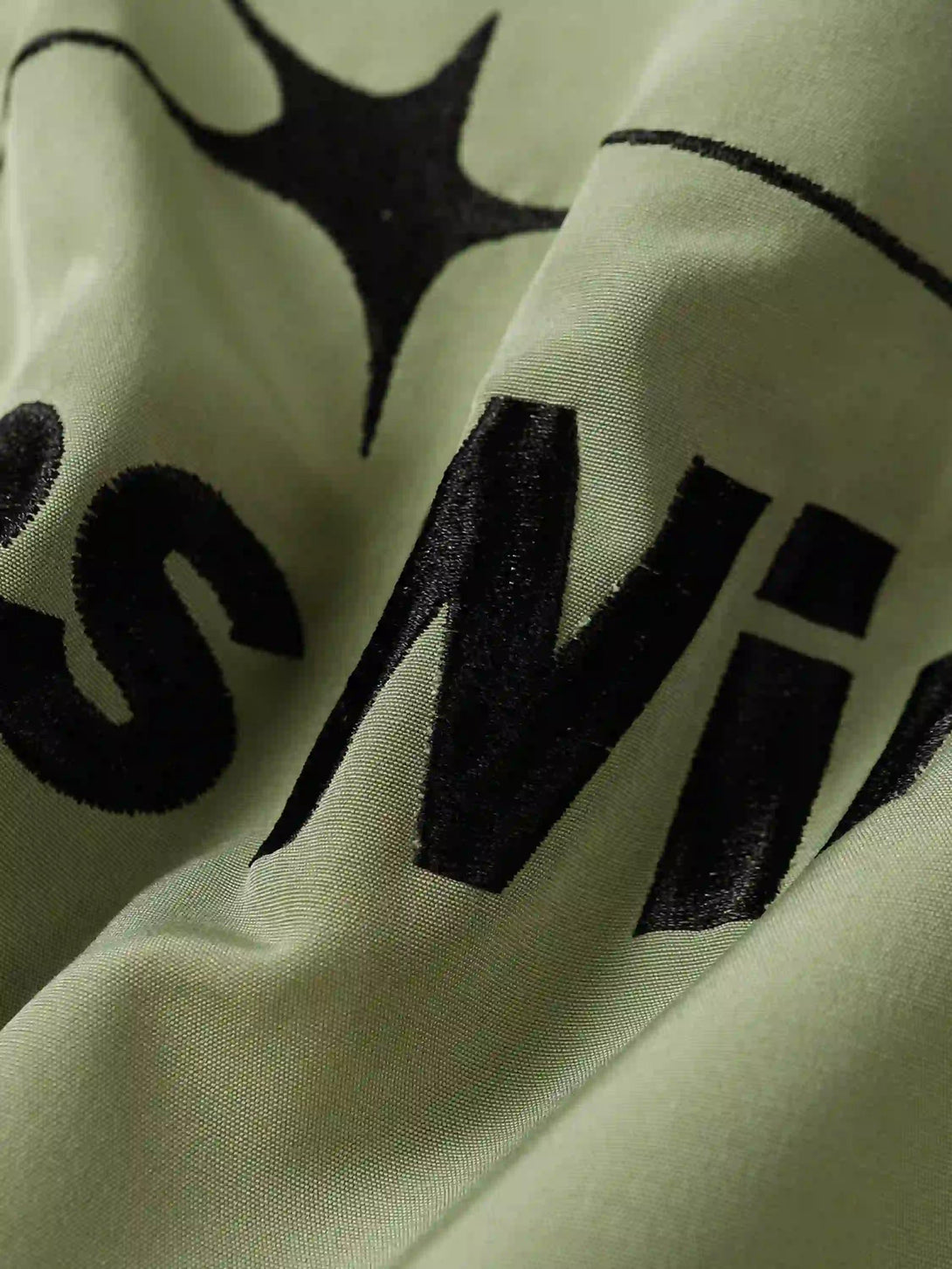 A close-up of TALISHKO's embroidered zip-up jacket, featuring bold star details and texture.