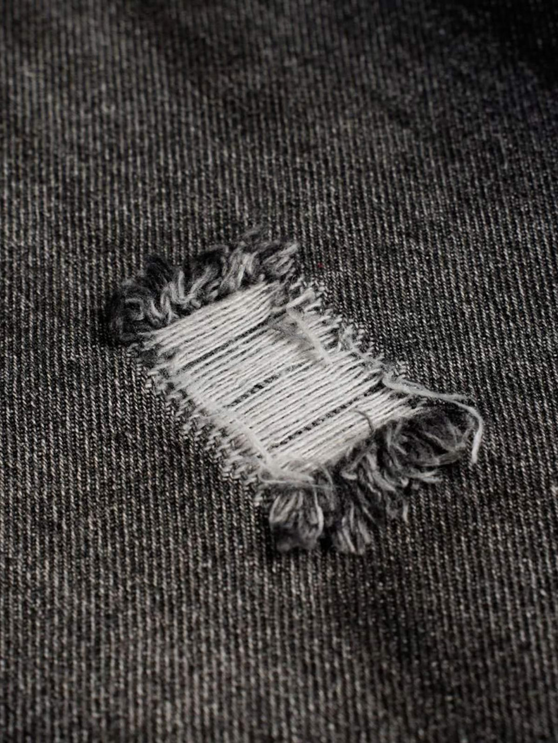 Frayed patch detail on dark denim fabric, showcasing texture and style by TALISHKO.