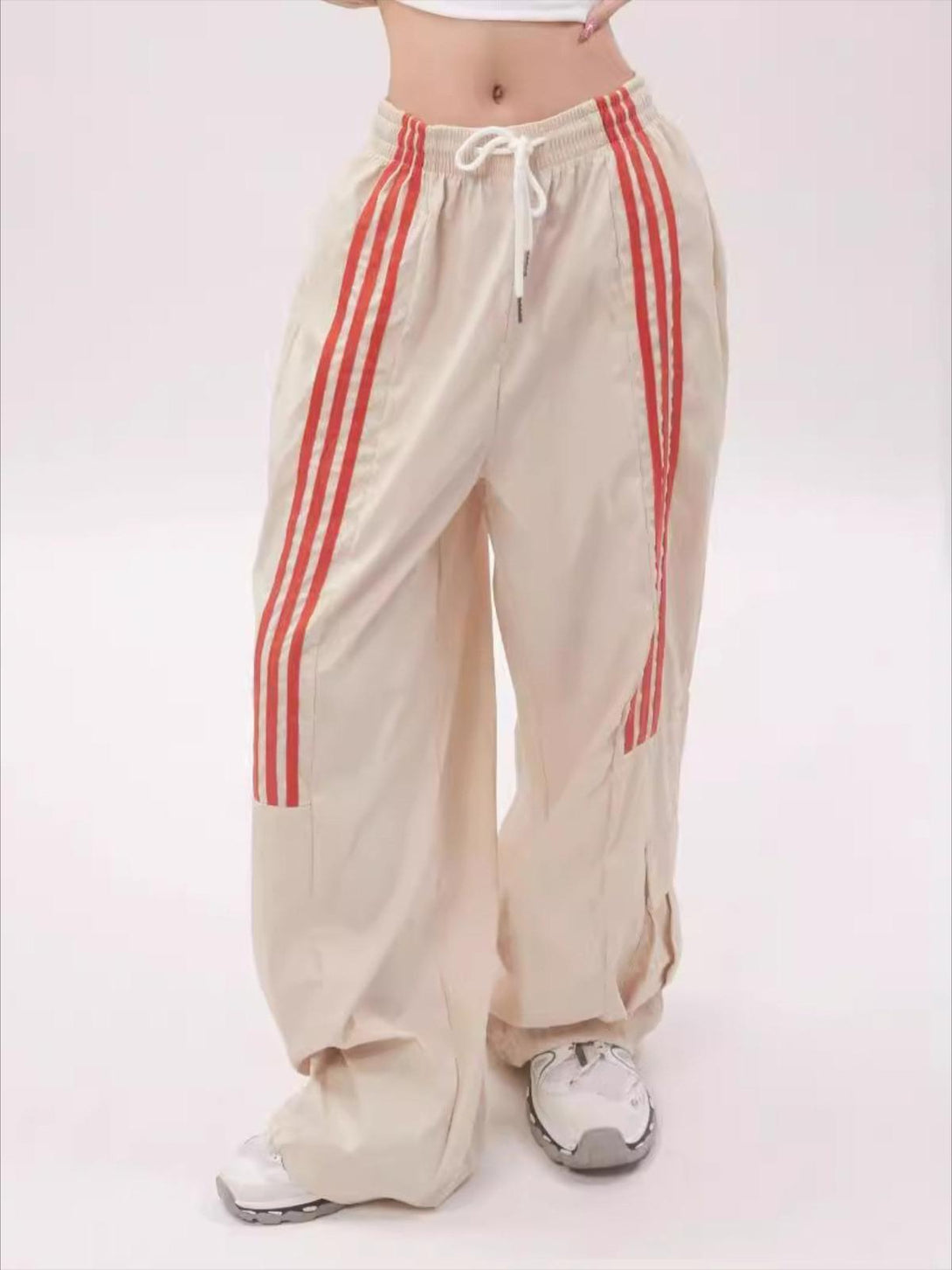 TALISHKO striped draped sweatpants in beige, featuring red stripes and a relaxed fit.