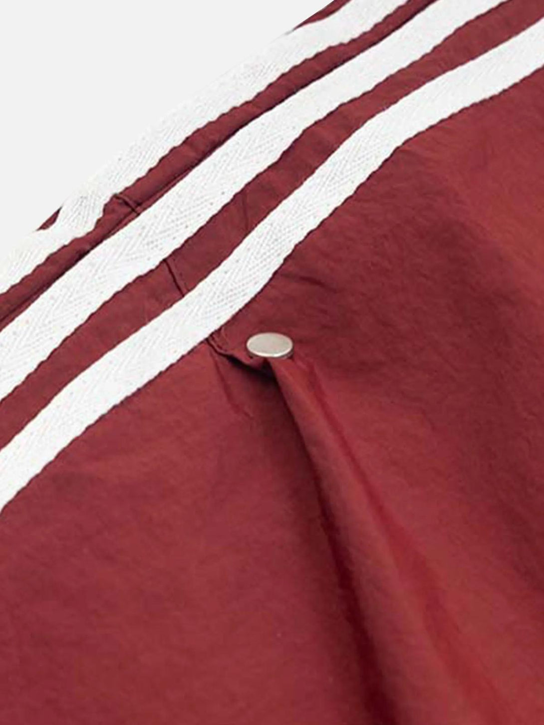 A tight crop highlighting the pleated design and stripes on TALISHKO's red sweatpants.