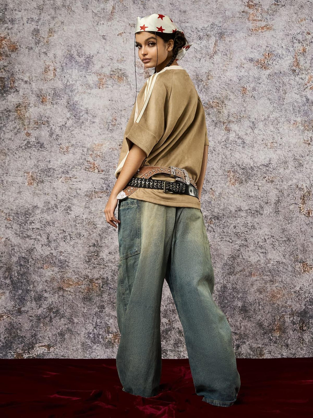 Model in a suede contrast oversized T-shirt by TALISHKO, styled with a studded belt and denim.