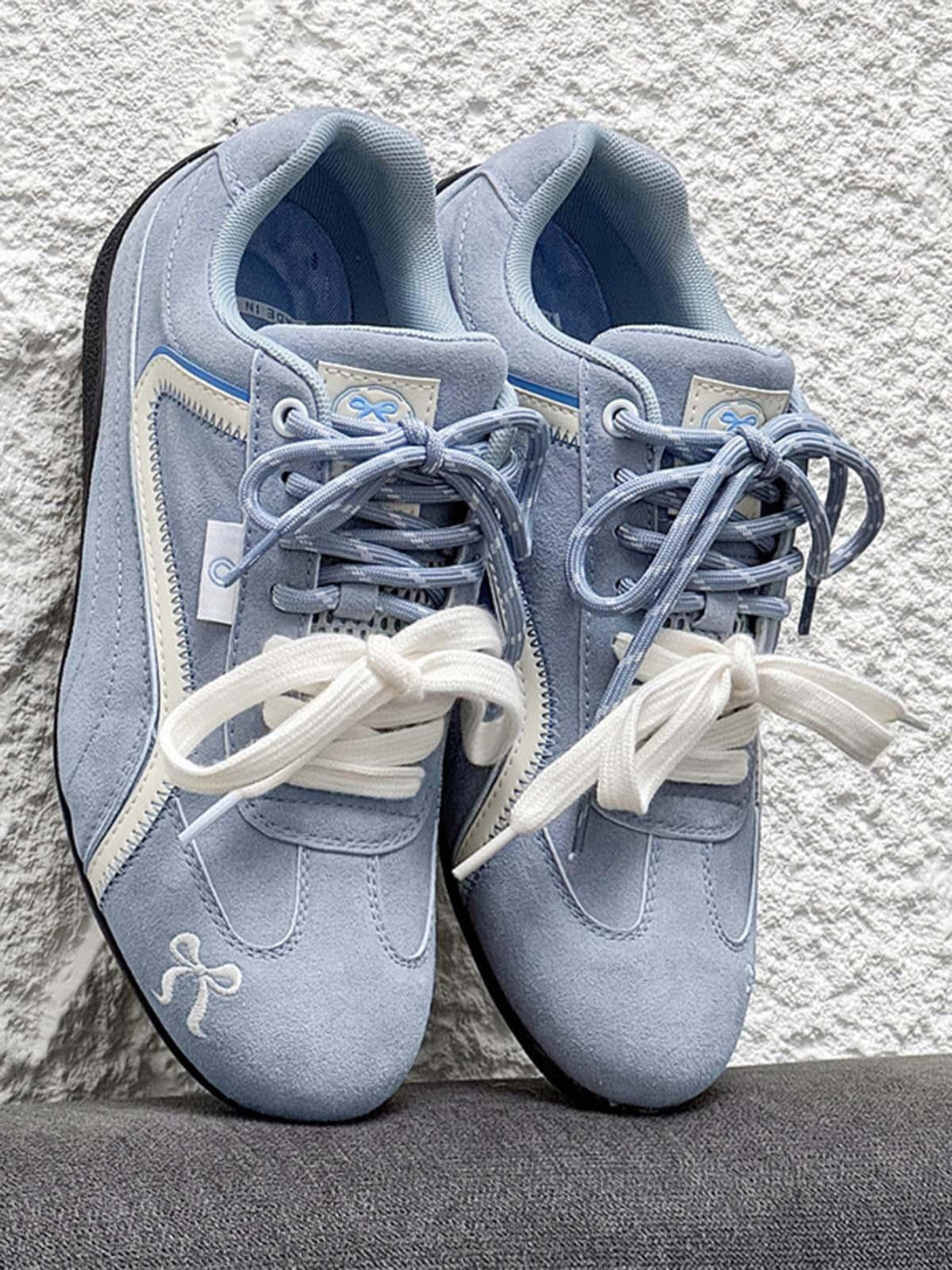 Light blue suede lace-up sneakers by TALISHKO, featuring playful embroidery and contrasting laces.