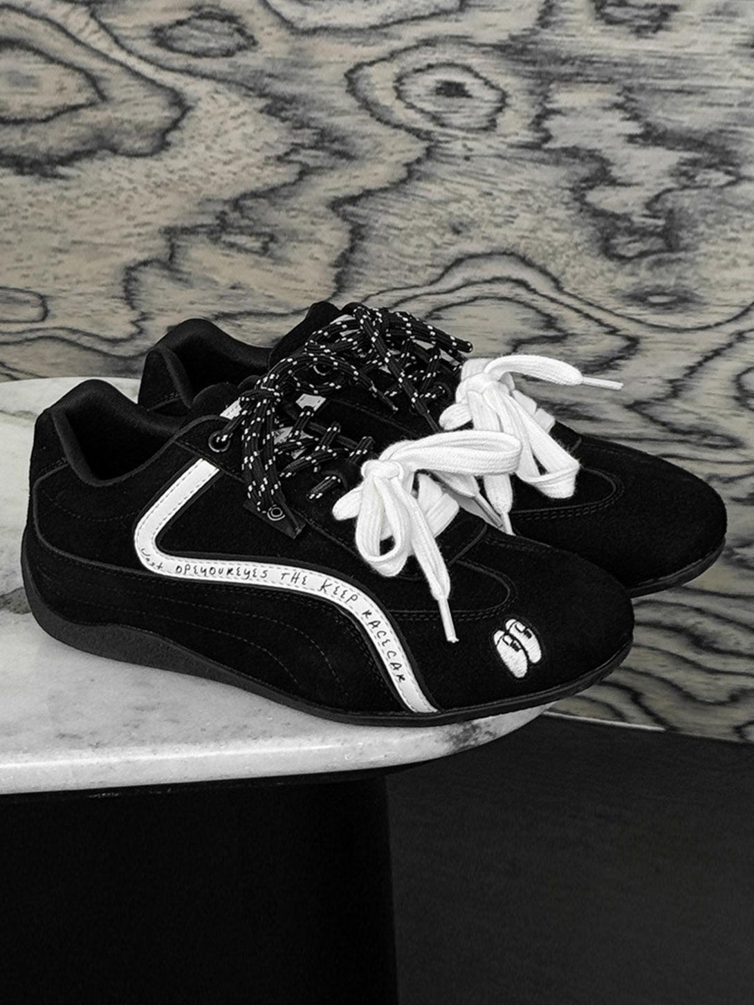 Black suede lace-up sneakers by TALISHKO, featuring unique embroidery and mixed laces.