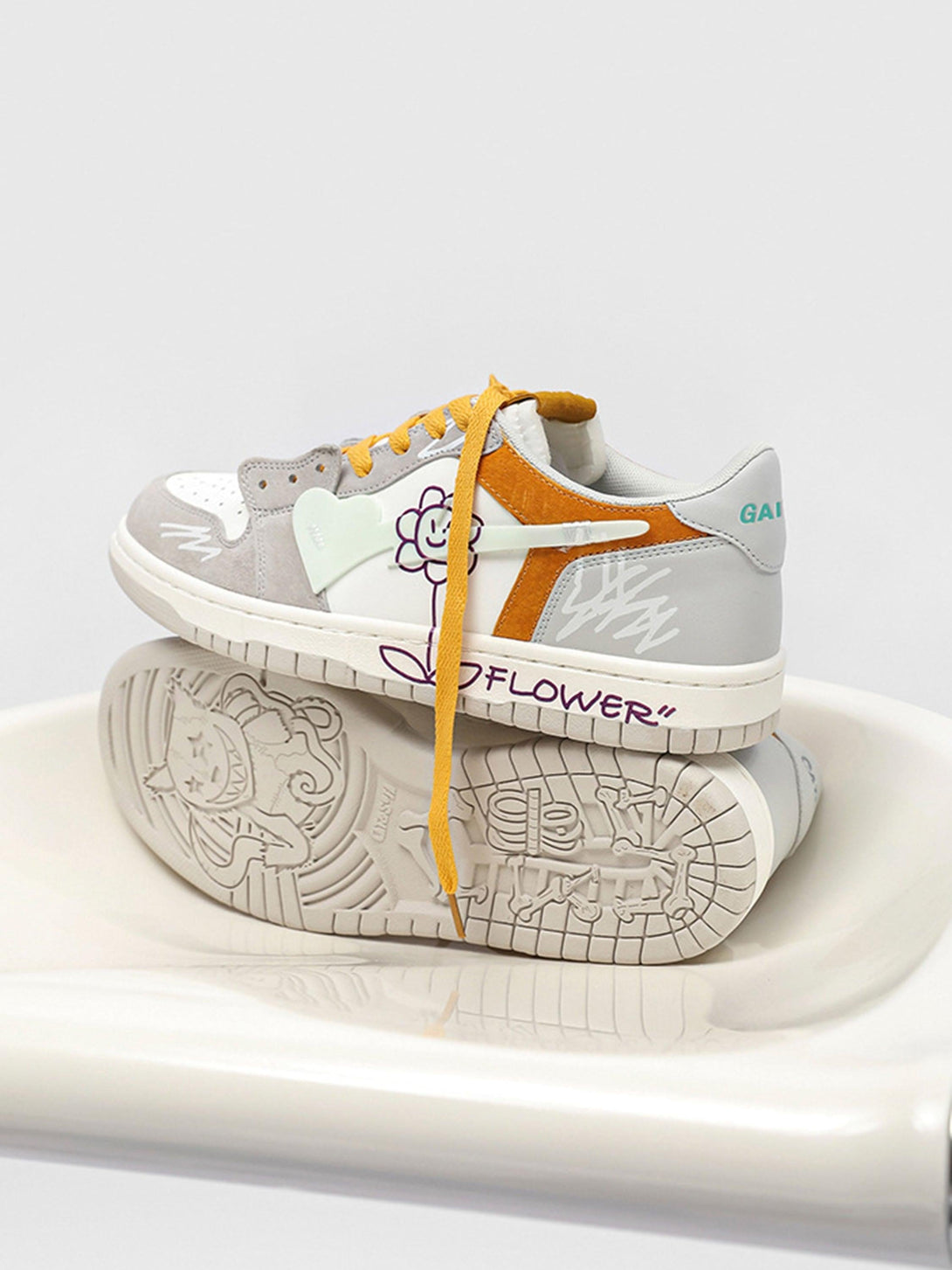 TALISHKO skate shoes with yellow laces and playful sunflower graphics, displayed on a chair.