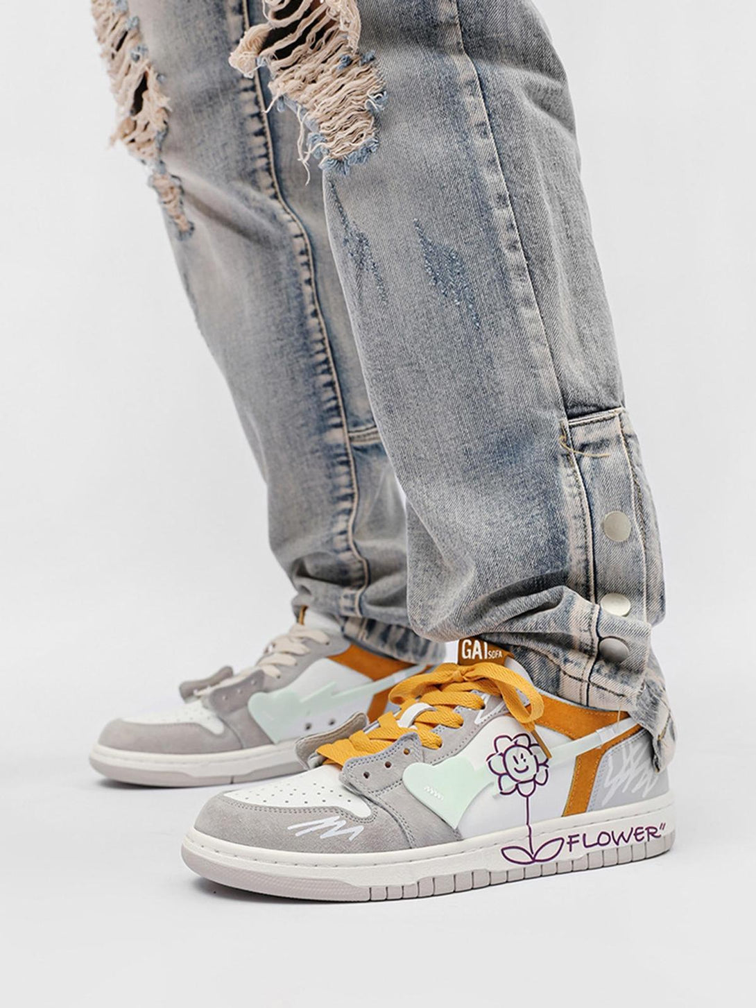 TALISHKO skate shoes feature playful flower graphics and yellow laces, styled with ripped jeans.