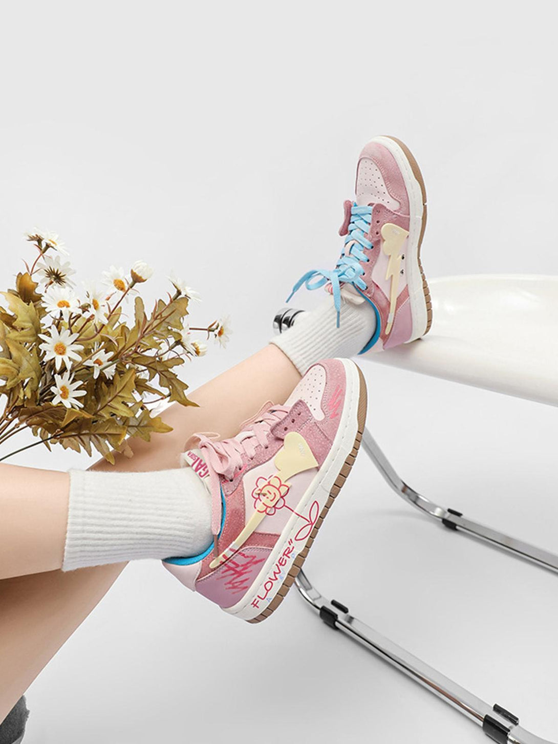 TALISHKO pink skate shoes with flower graphics and mismatched laces, styled with white socks.