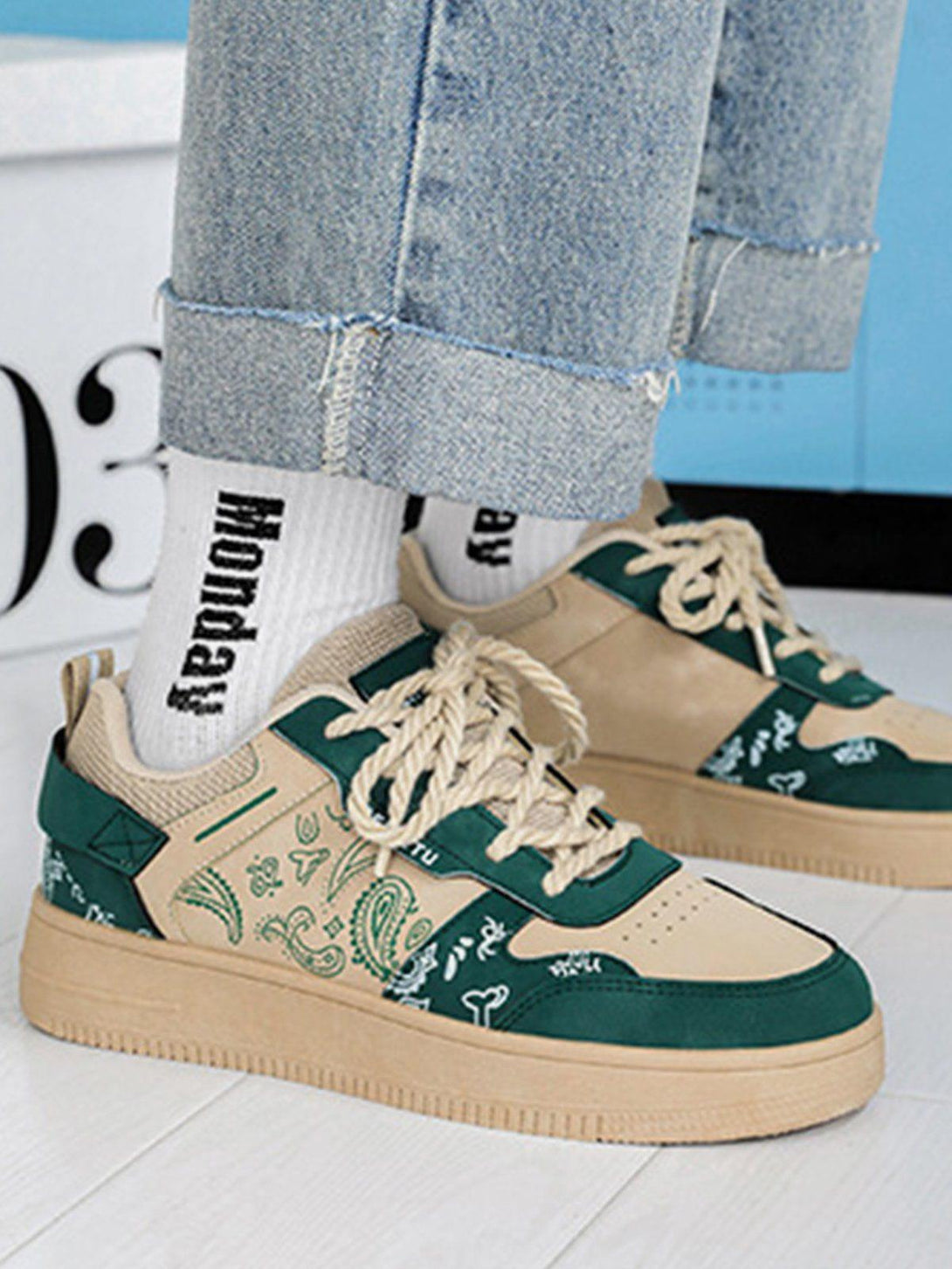 TALISHKO men's shoes with green and tan cashew flower print, worn with rolled-up jeans.