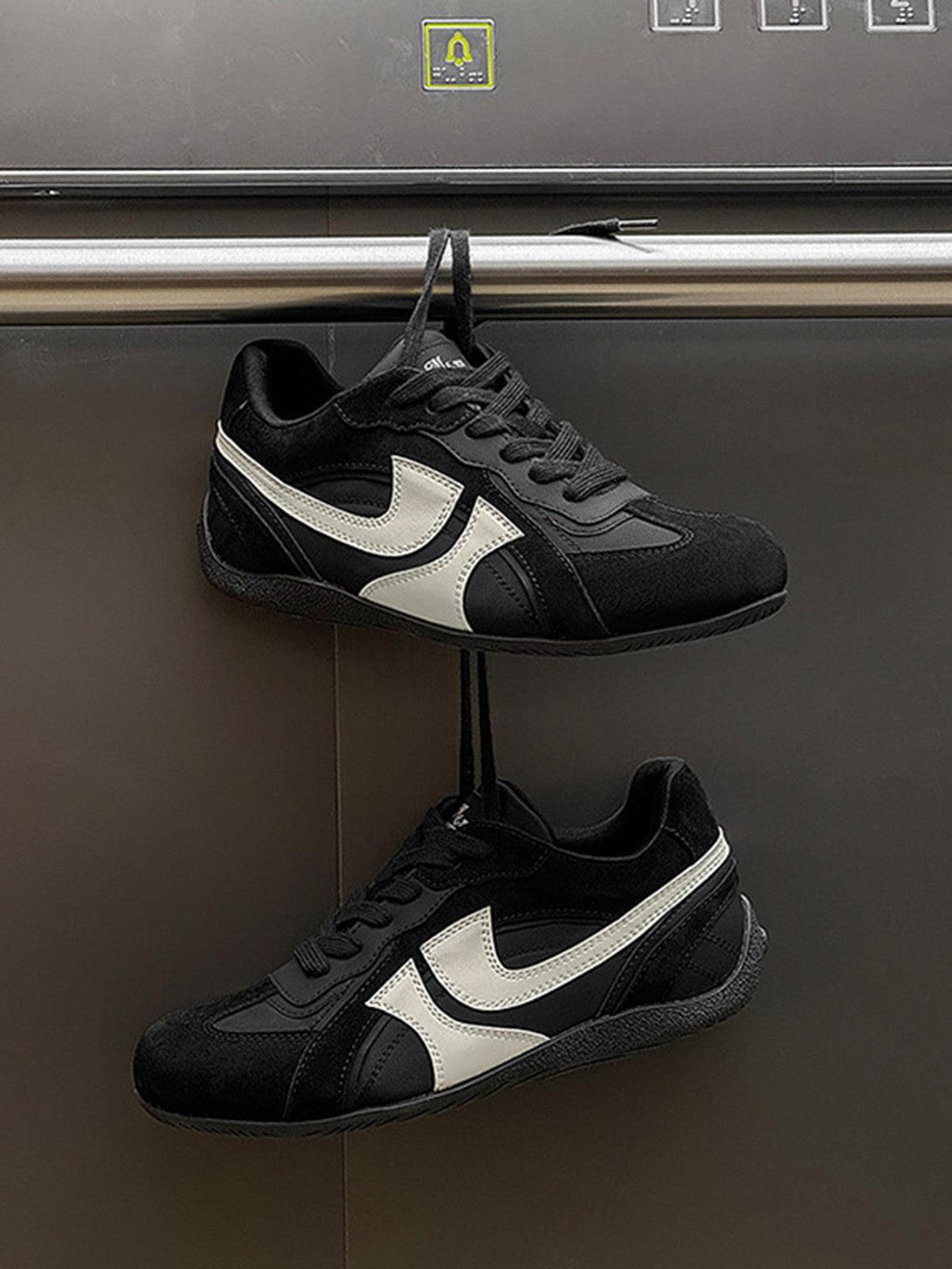 TALISHKO black suede low-top sneakers with white accents, displayed from the front.