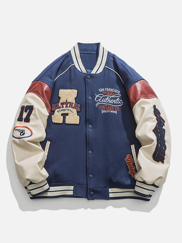 Navy varsity jacket by TALISHKO with bold patches and contrast stitching, front view.