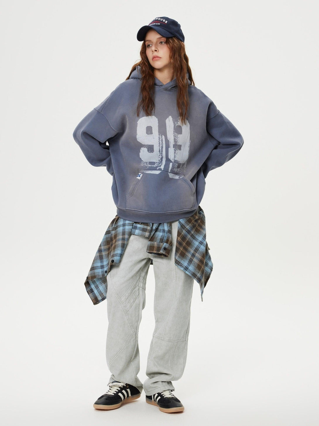 Model wearing gray TALISHKO hoodie and patchwork jeans, with plaid shirt tied at the waist.