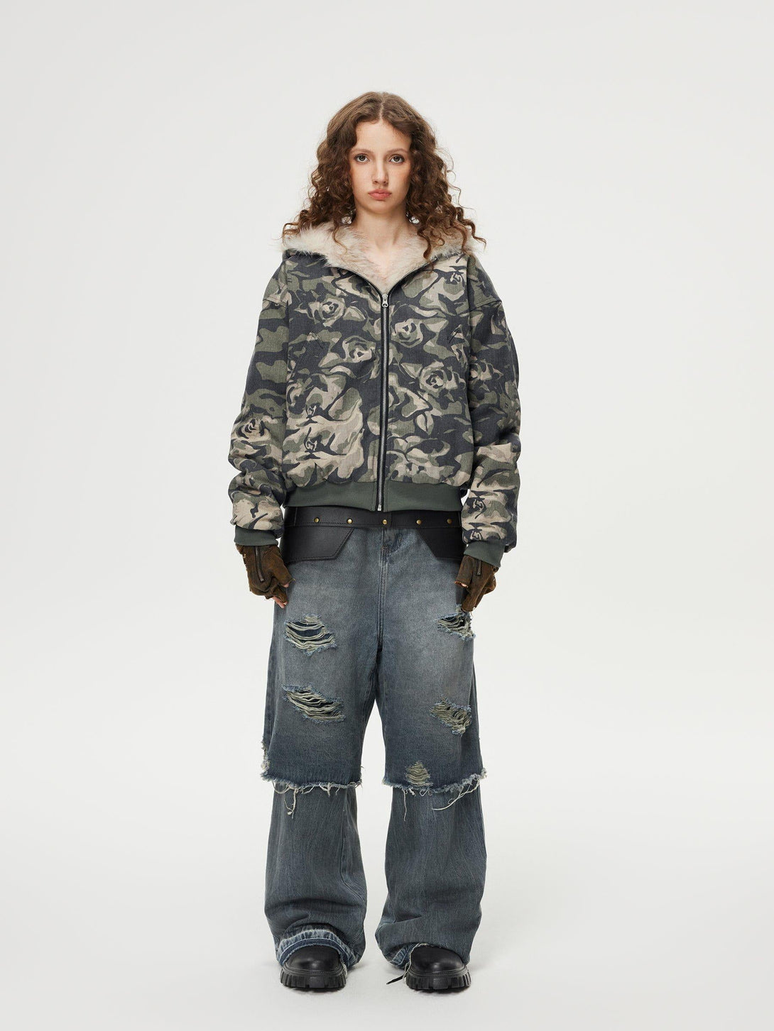 Model wears TALISHKO distressed baggy jeans with layered design, showcasing edgy street style.