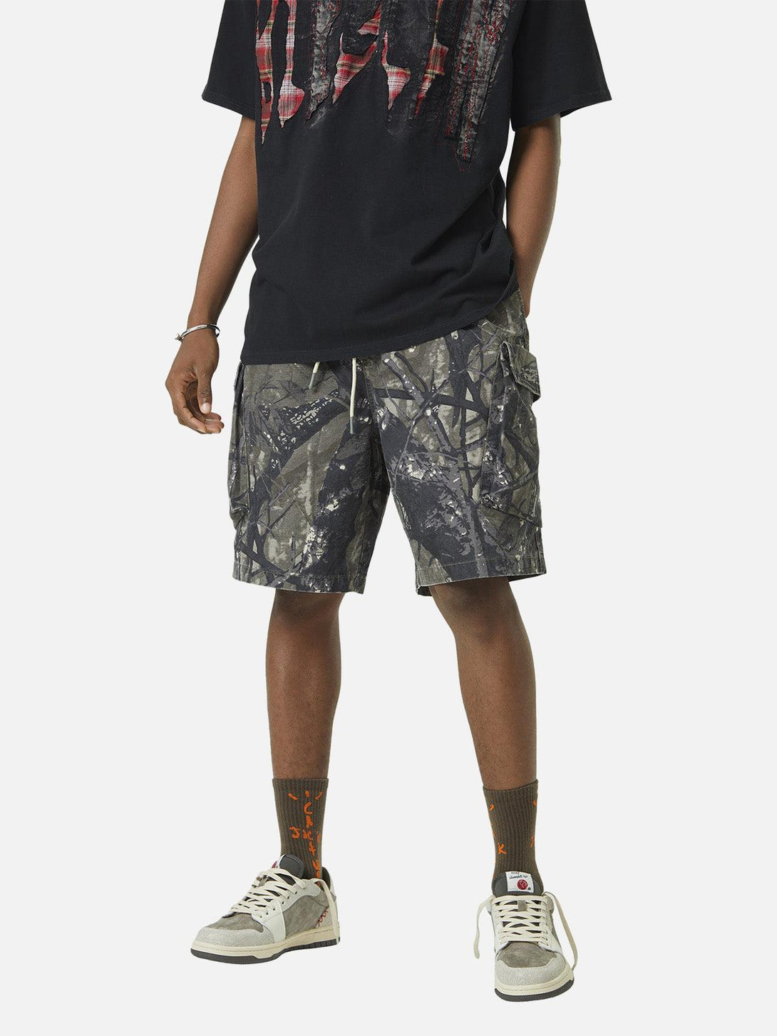 Model wearing TALISHKO camouflage shorts in army green with bold pocket details, front view.