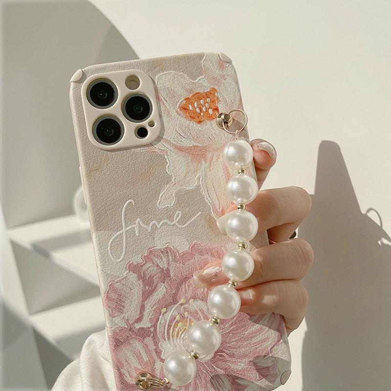 A close-up of a TALISHKO iPhone case with elegant floral design and a stylish pearl strap.