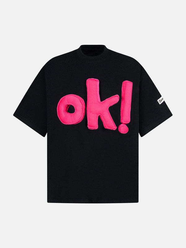 Front view of black graphic T-shirt with bold pink "OK!" design by TALISHKO.