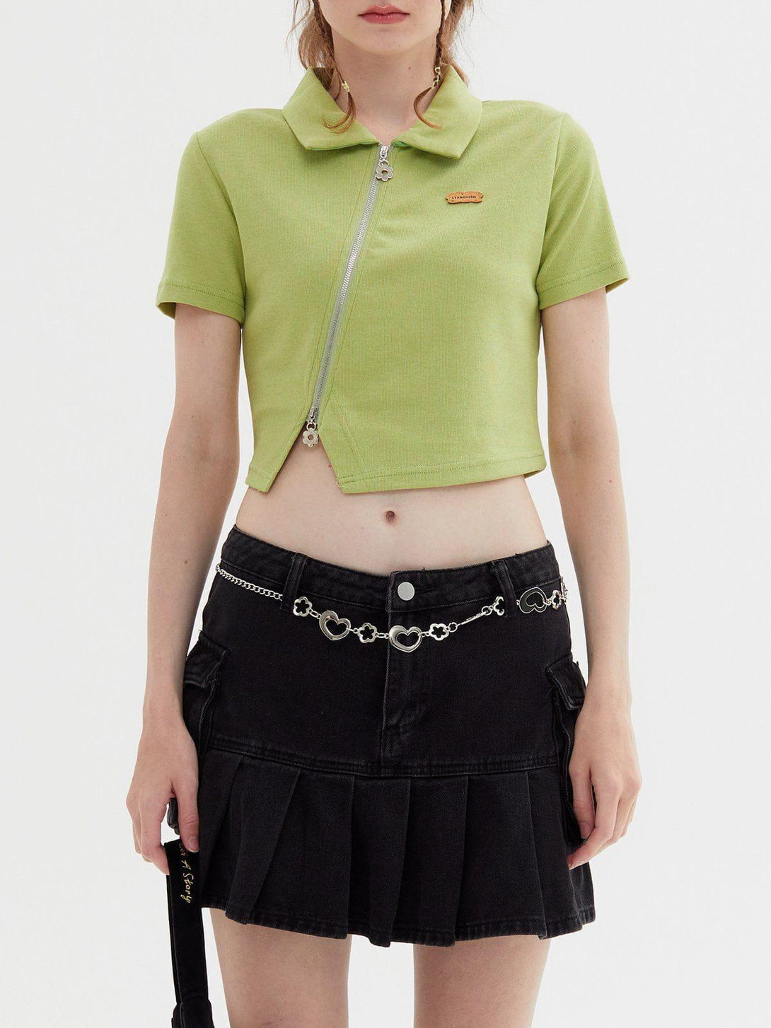Model wearing a green geometric zip-up crop tee by TALISHKO, paired with a black skirt.